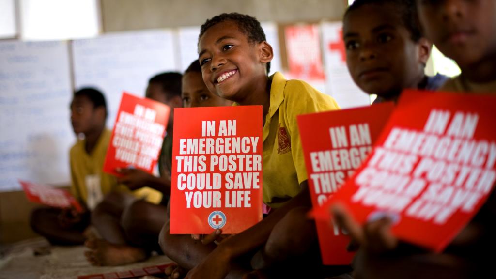 Students in a classroom in Fiji hold disaster risk reduction posters