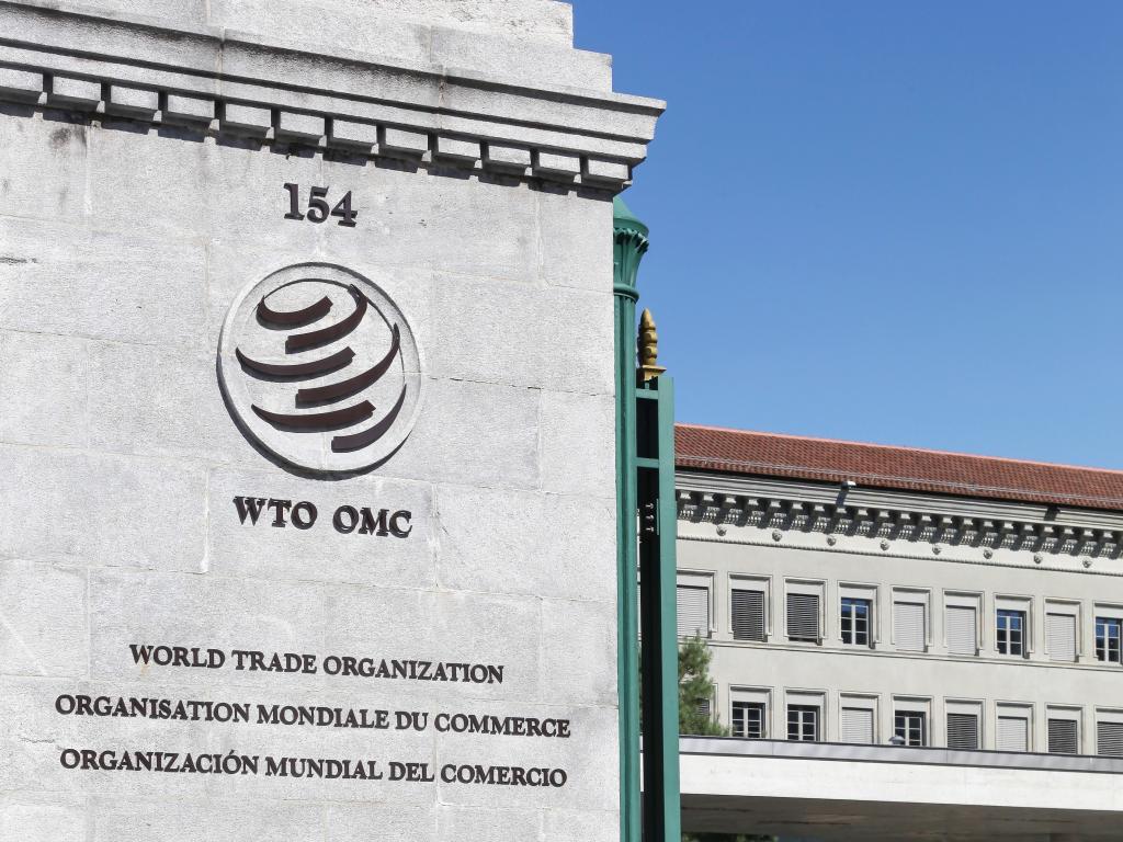 A pillar with the World Trade Organization logo and a building in the background