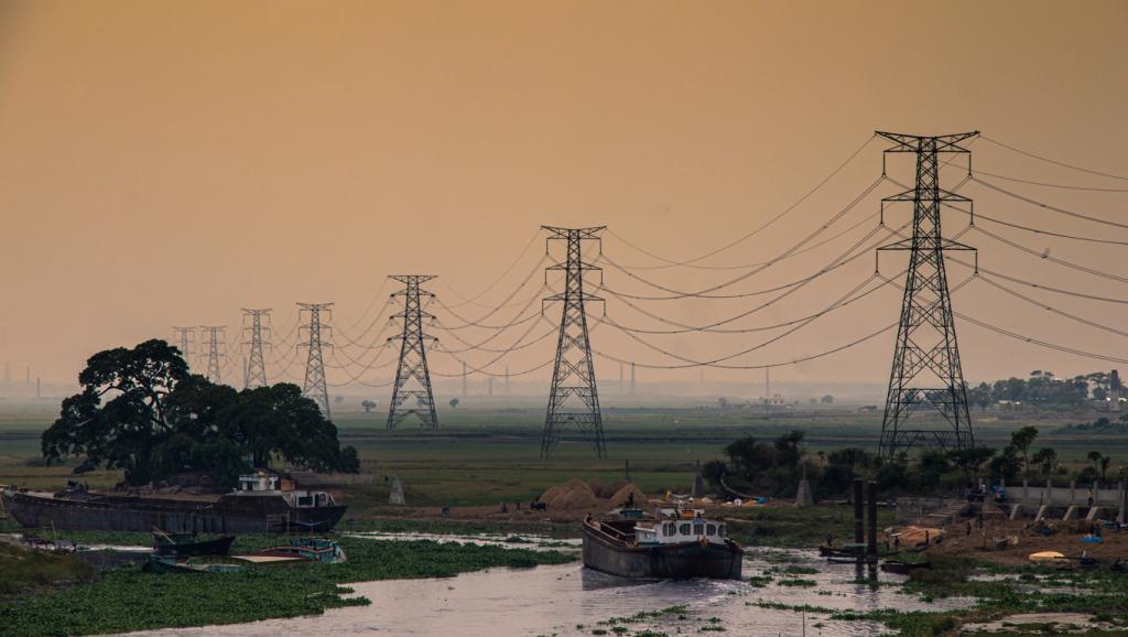 Transmission towers stand behind the Turag River in Bangladesh