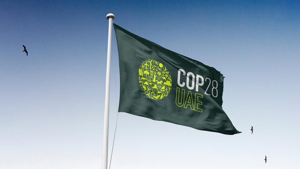 Flag with COP 28 floating under blue sky