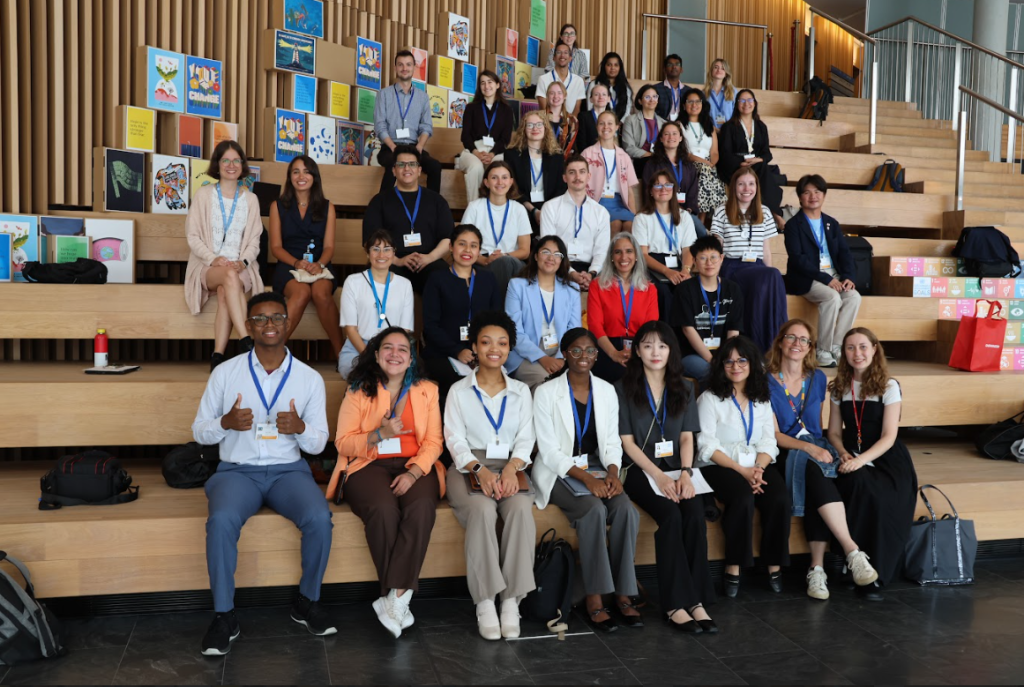 Group of diverse, young people sit on stairs looking at the camera and smiling