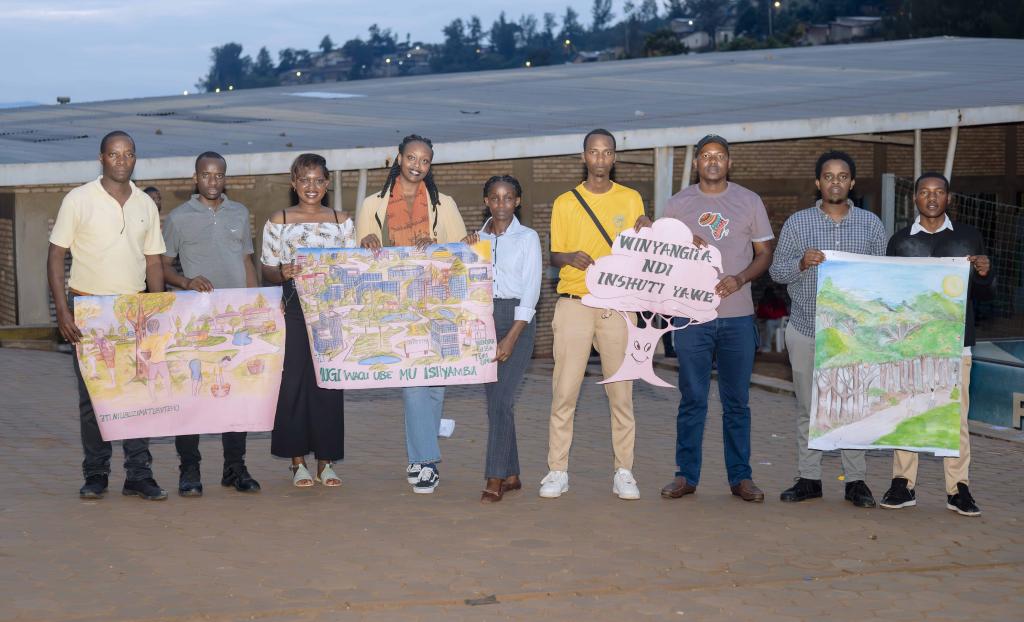 Nine people stand and pose for a photo. They hold up artwork to the camera in pairs.