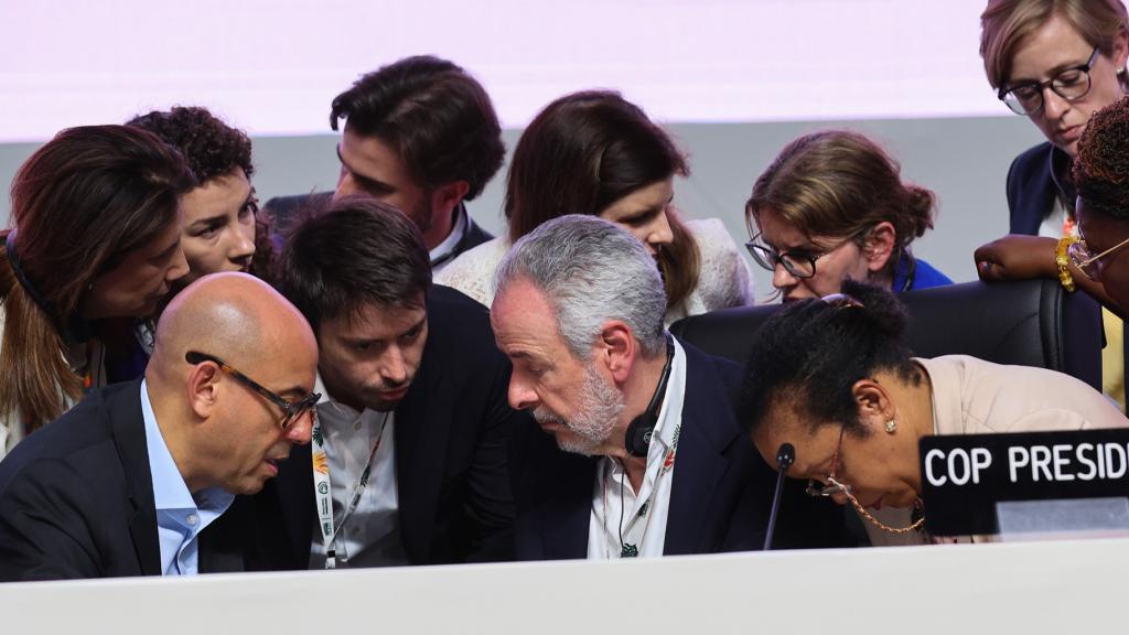 Members of the COP 30 presidency and UNFCCC huddle at the dias.