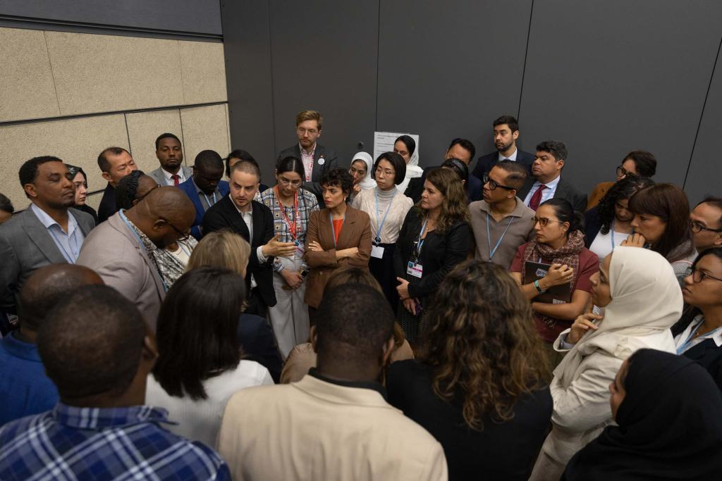 Delegates huddle during the informal consultations on the Global Goal on Adaptation (GGA) at the 2026 Bonn Climate Change Conference.