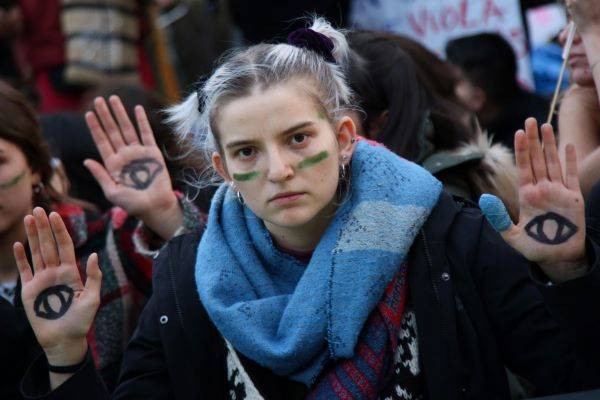 Young woman at climate protest holds up hands to the camera