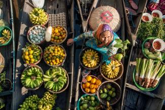An overhead shot of a woman in a boat full of produce.