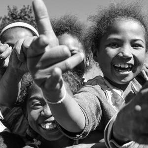 A closeup group of children smiling, throwing hand gestures to the camera.