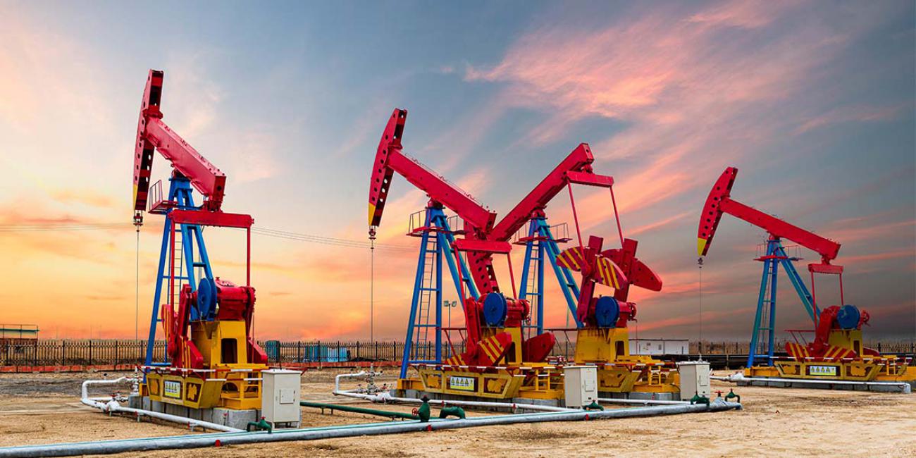 Oil wells stand in front of a sunrise.