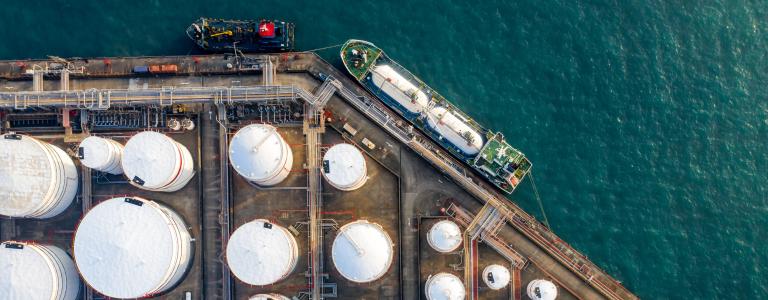 Oil refinery storage units with tanker ship viewed from above