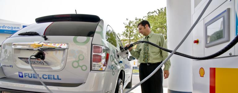 A man recharges a hydrogen fuel cell SUV at a gas station